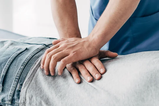 Chiropractor performing a lower back adjustment on a patient.