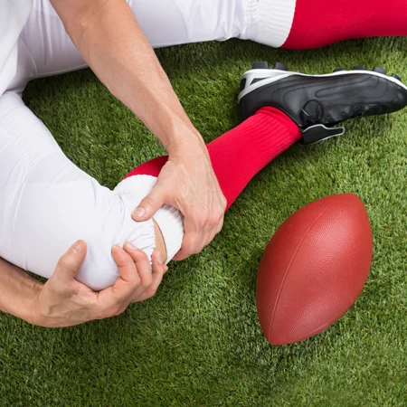 Football player holding an injured knee on the field.